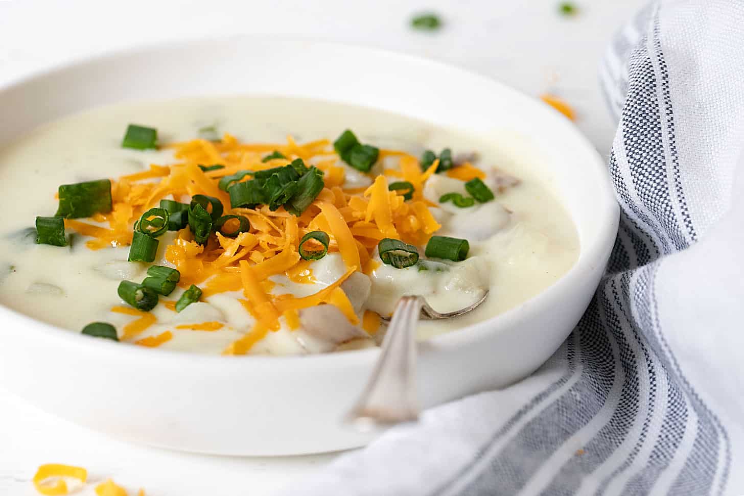 loaded baked potato soup in white bowl with spoon
