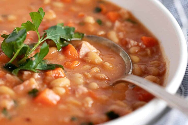 bean and ham soup in white bowl with spoon