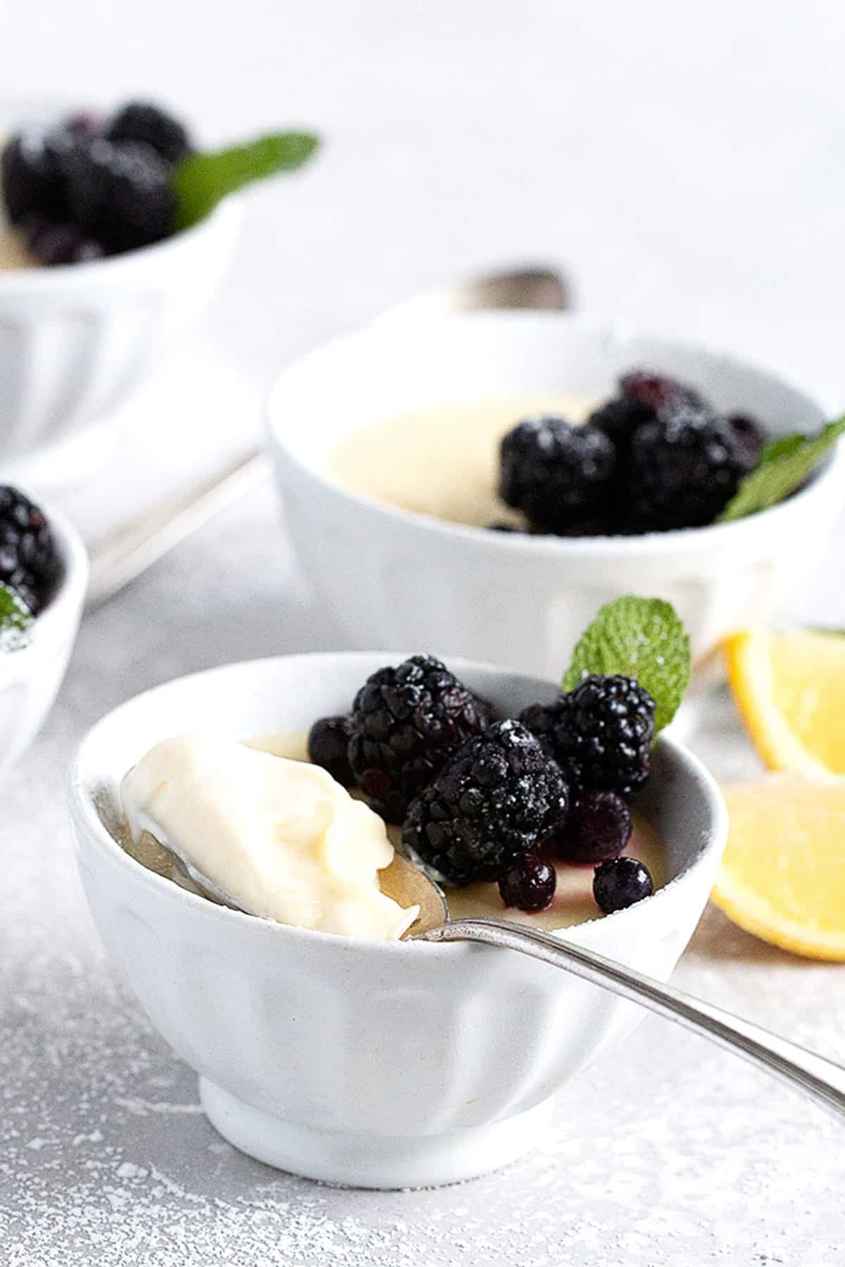 lemon posset in small white bowls with berries on top