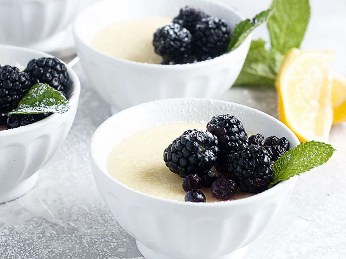 lemon posset in small white bowls with berries on top