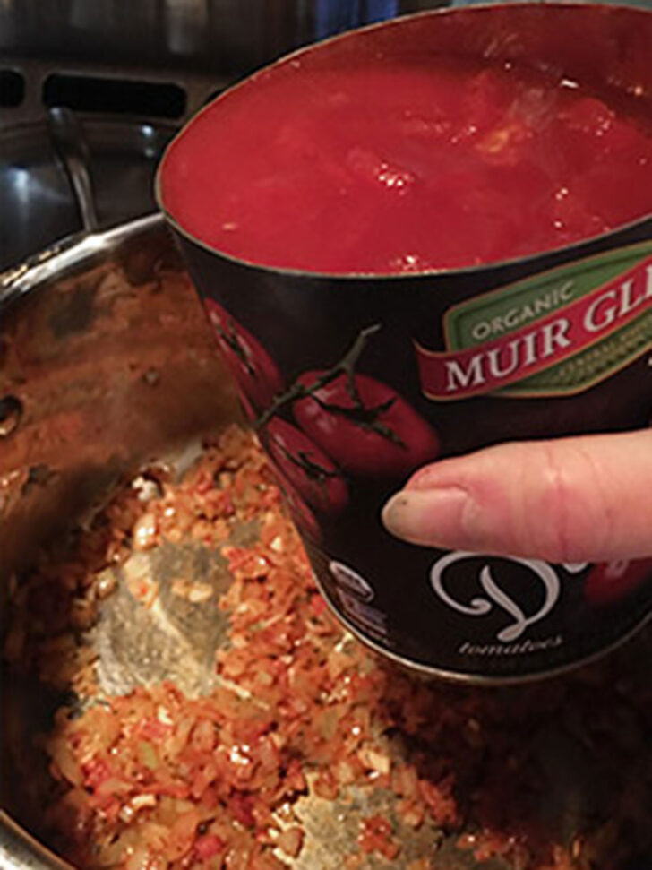 Adding the canned tomatoes to the pot,