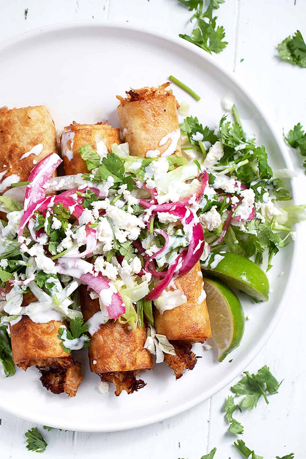 chicken flautas on plate with garnishes