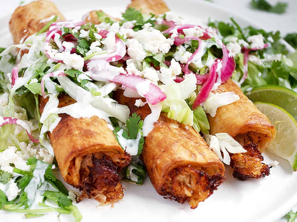 chicken flautas on plate with garnishes