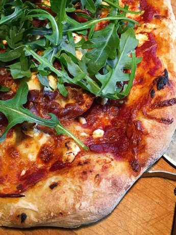 homemade gourmet pizza on cutting board with pizza cutter