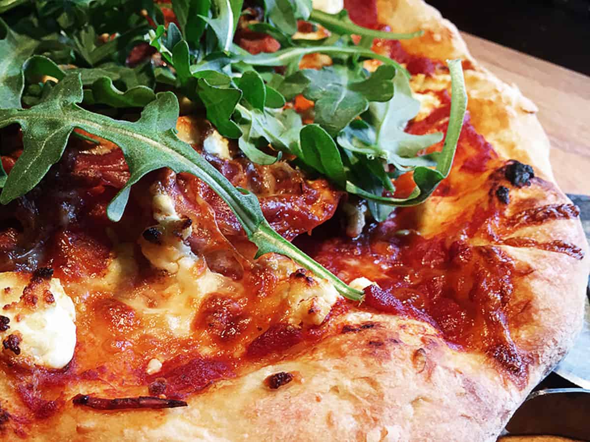 homemade gourmet pizza on cutting board with pizza cutter