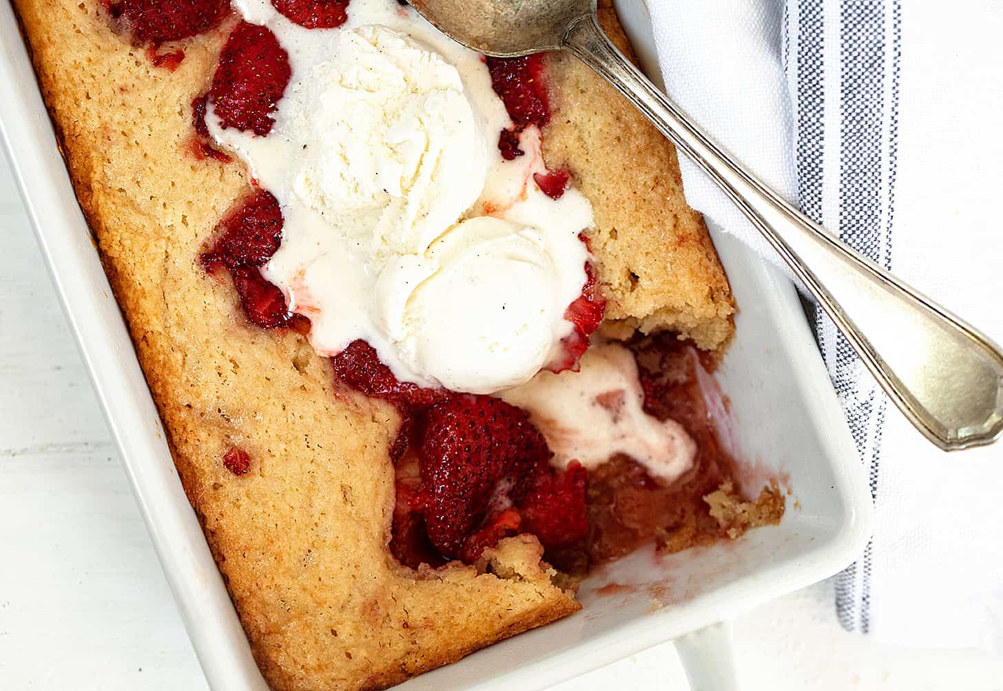 strawberry spoon cake in baking dish with ice cream