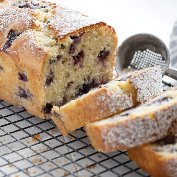 Blueberry buttermilk loaf sliced on a cooling rack.