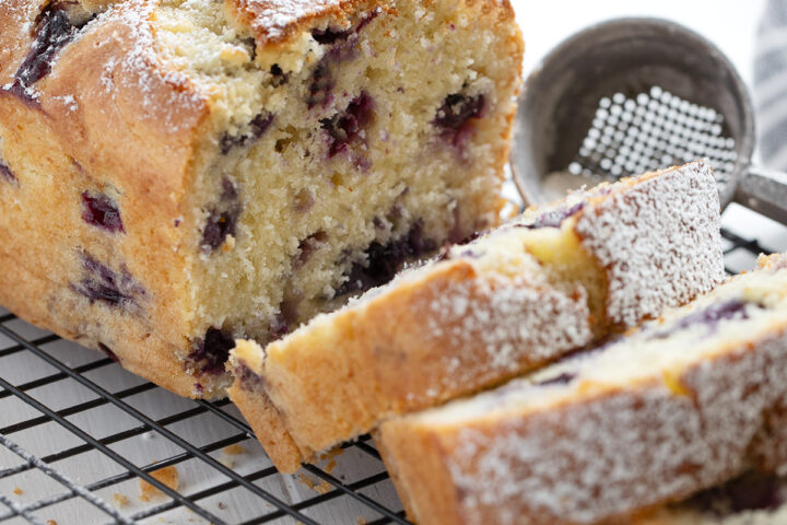 Blueberry buttermilk loaf sliced on a cooling rack.