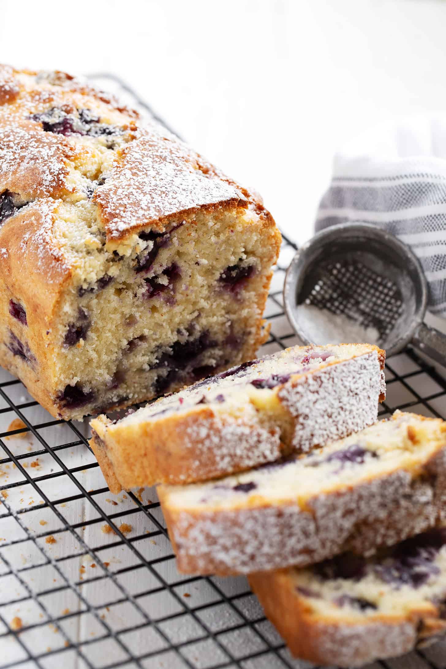 Blueberry buttermilk loaf sliced on a cooling rack.