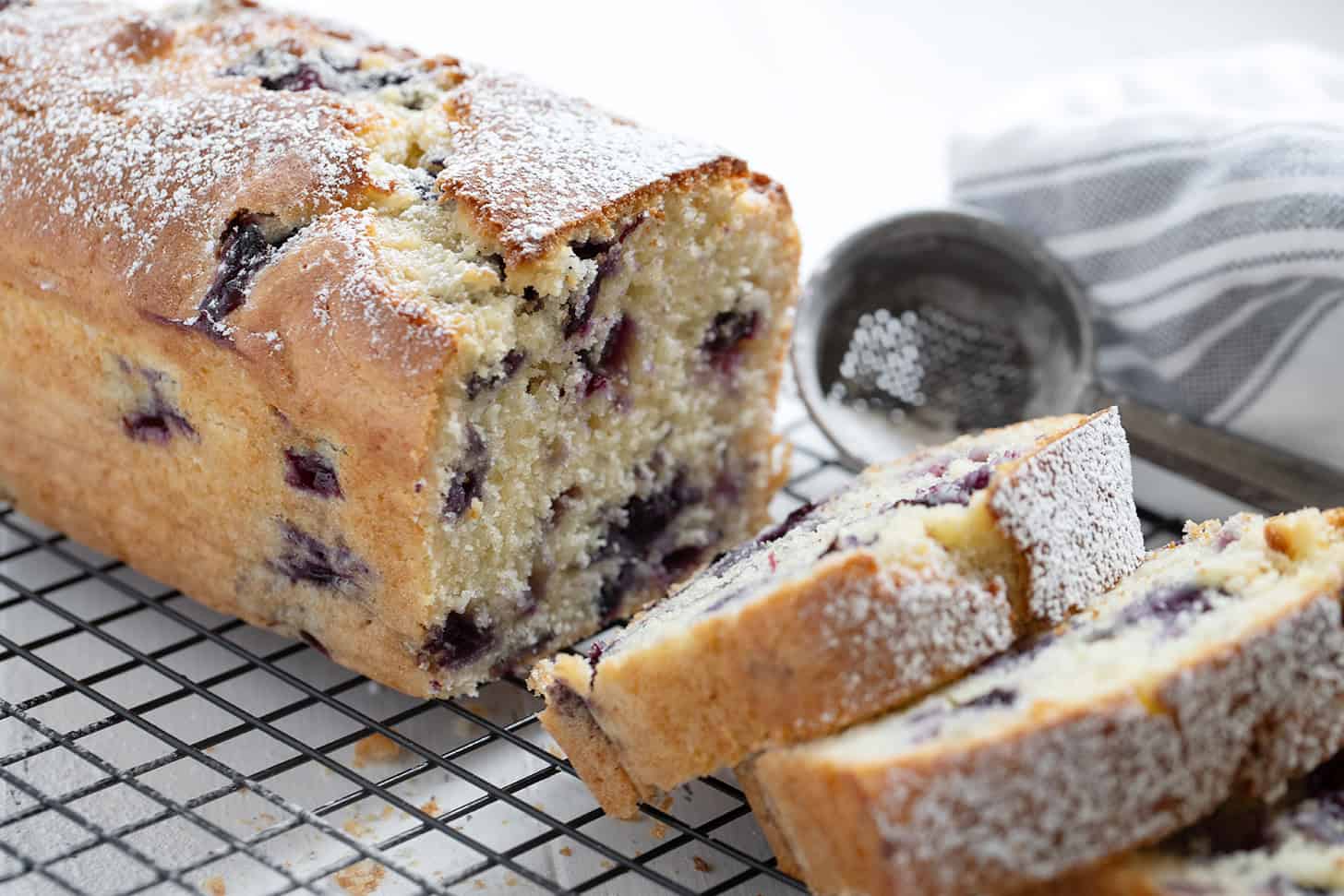 Blueberry buttermilk loaf sliced on a cooling rack.