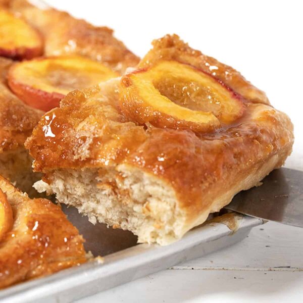 Baltimore peach cake in pan with slice