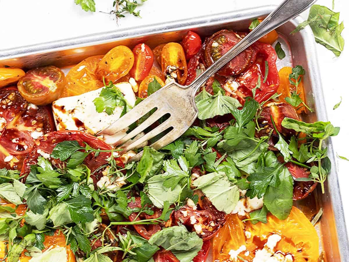 roasted heirloom tomatoes with feta and herbs on baking sheet