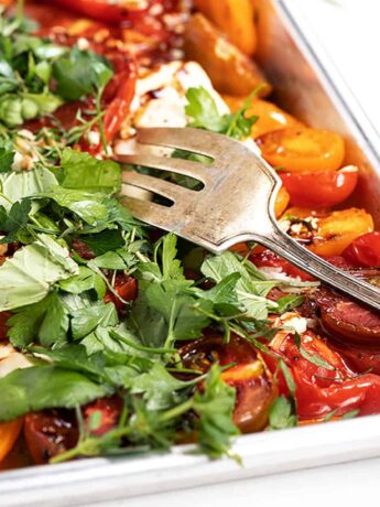 roasted heirloom tomatoes with feta and herbs on baking shee