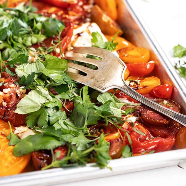 roasted heirloom tomatoes with feta and herbs on baking shee