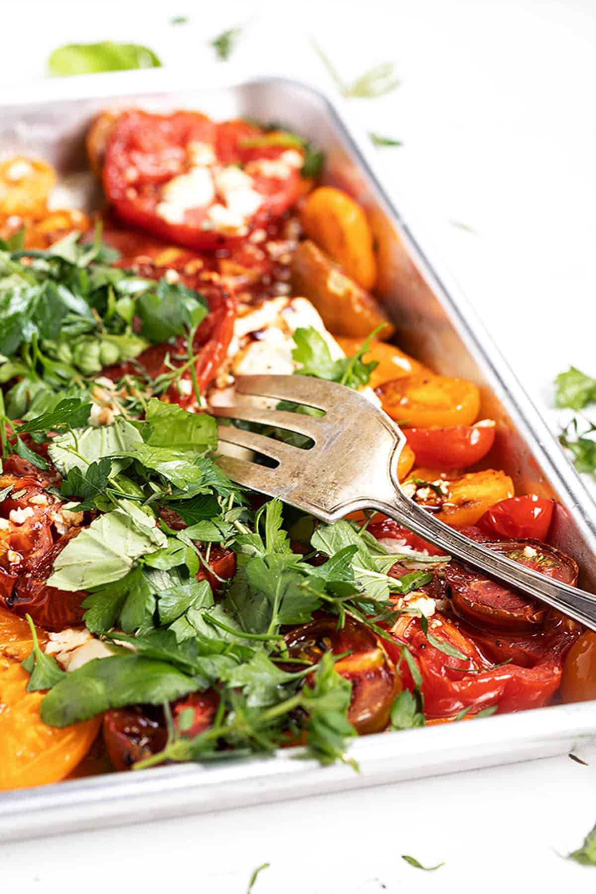 roasted heirloom tomatoes with feta and herbs on baking shee