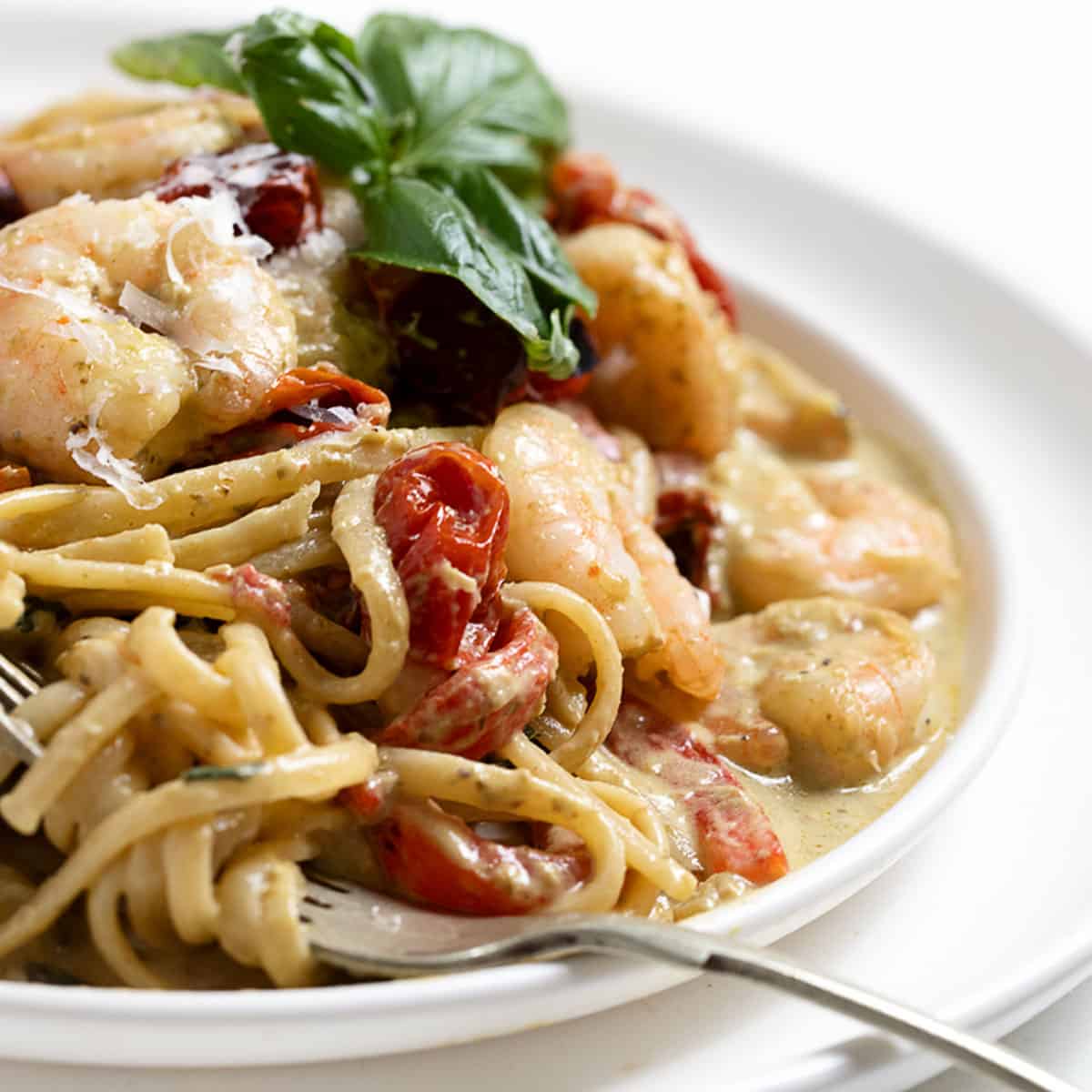 Pasta with shrimp and pesto sauce on plate with fork