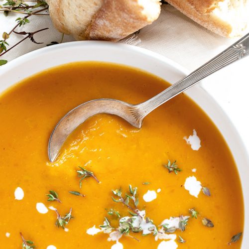 roasted butternut squash soup in white bowl with bread on the side