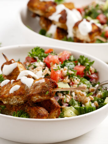 Chicken shawarma skewers served with a grain salad.