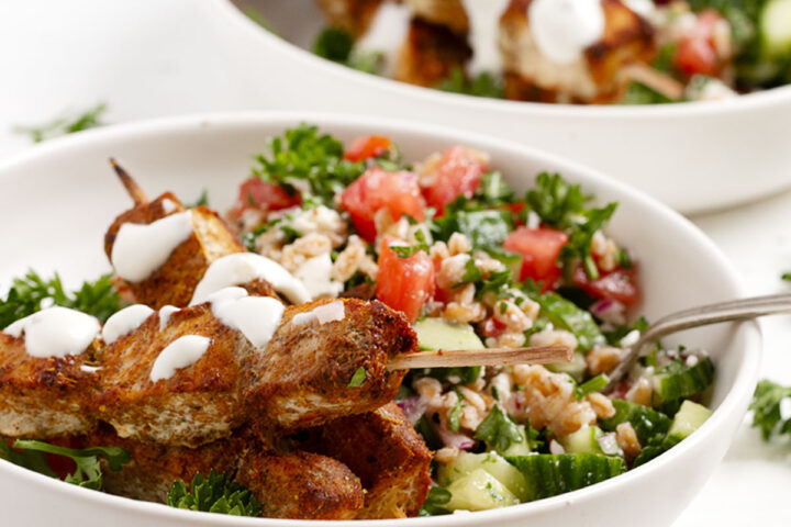 Chicken shawarma skewers served with a grain salad.