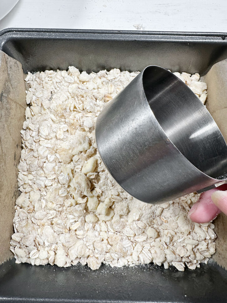 Pressing some of the flour mixture into the bottom of the baking pan.