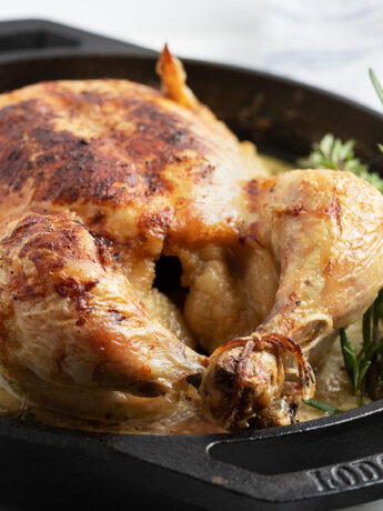 milk braised whole chicken in skillet with herbs