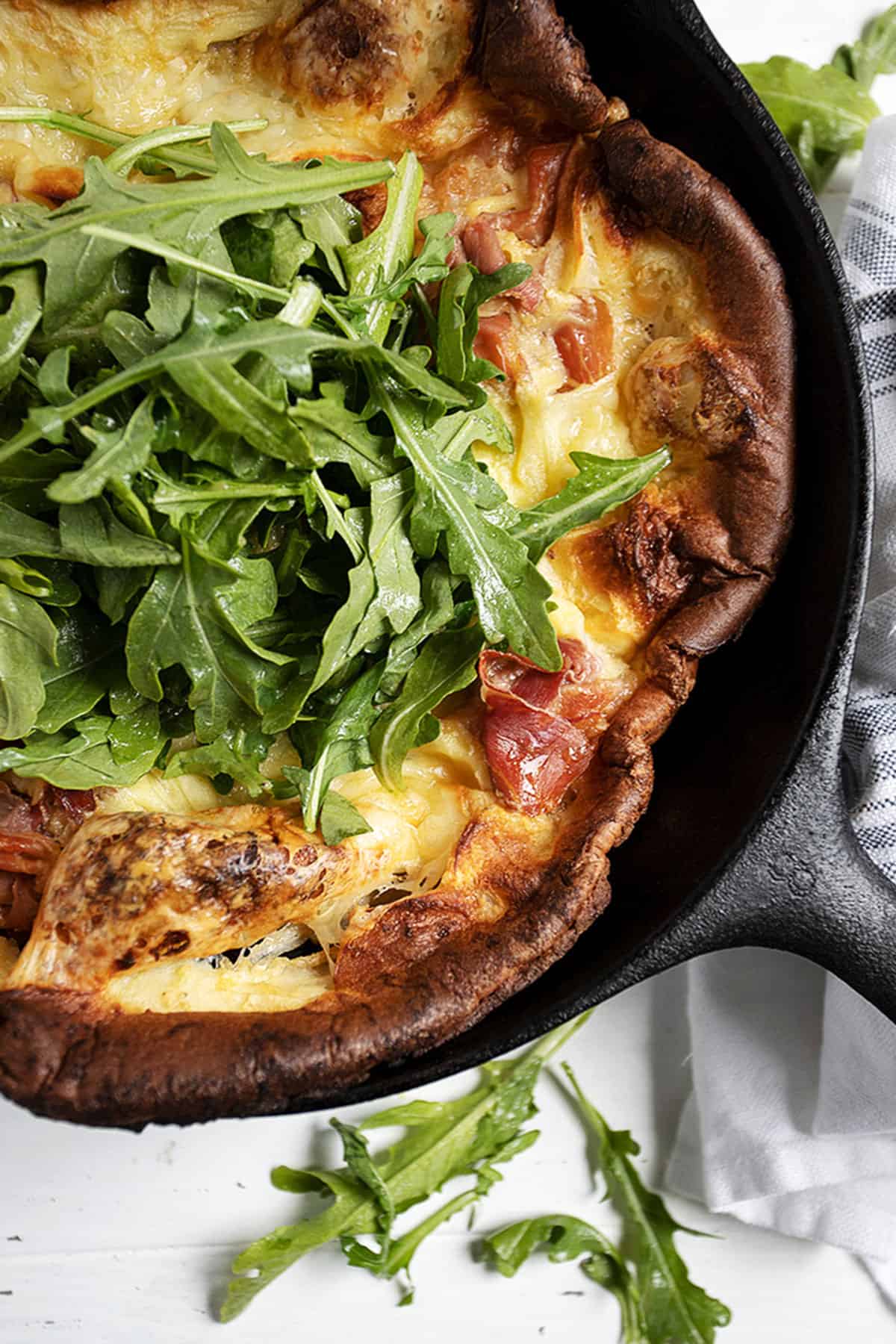 prosciutto Dutch baby in skillet with arugula