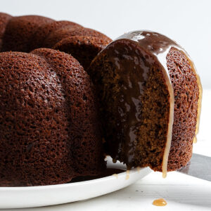 sticky toffee bundt cake sliced on plate with toffee sauce