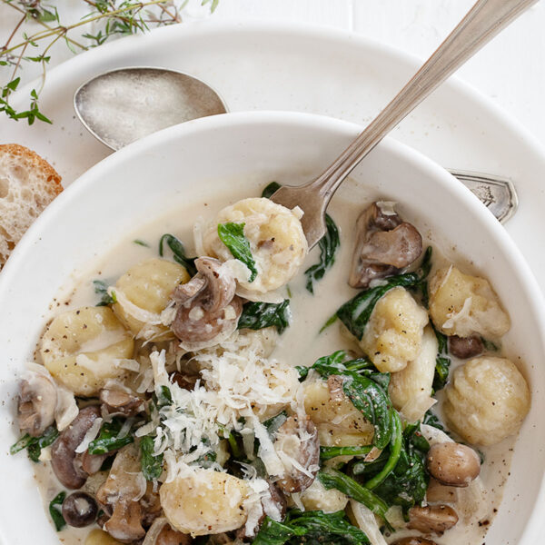 gnocchi with mushrooms and spinach in bowl with fork