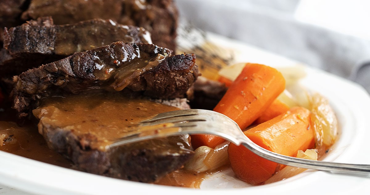 pot roast sliced with gravy, carrots and onions