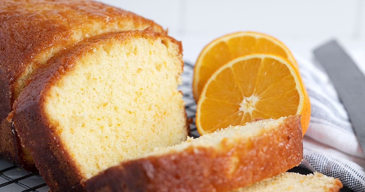 orange drizzle cake loaf, sliced with halved orange