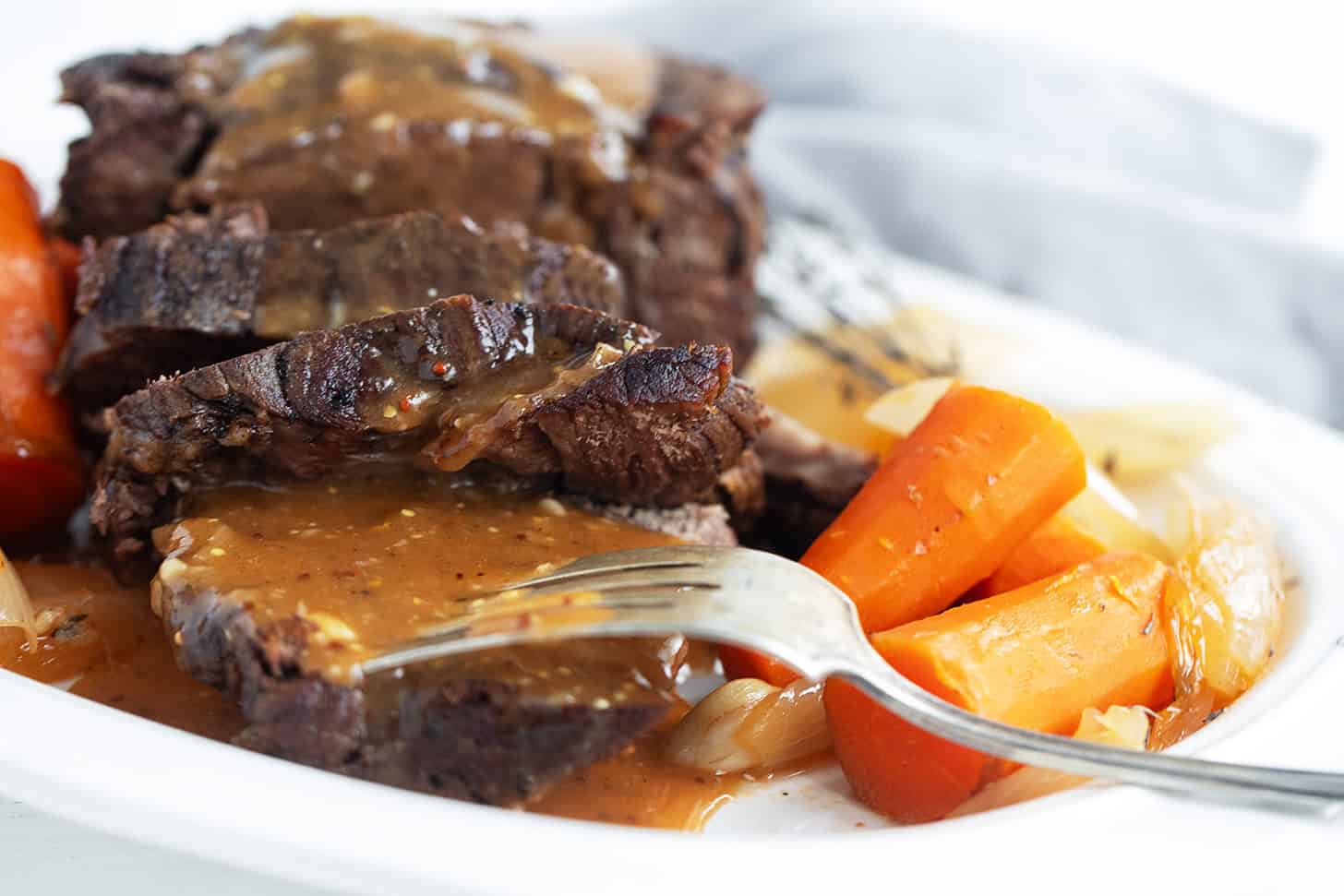 Pot roast with horseradish gravy sliced on a plate.