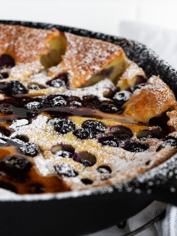 blueberry Dutch baby with sausage in cast iron skillet