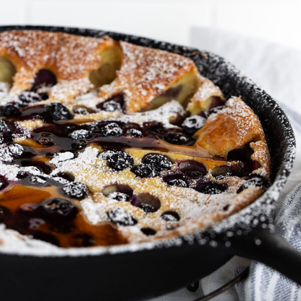 blueberry Dutch baby with sausage in cast iron skillet