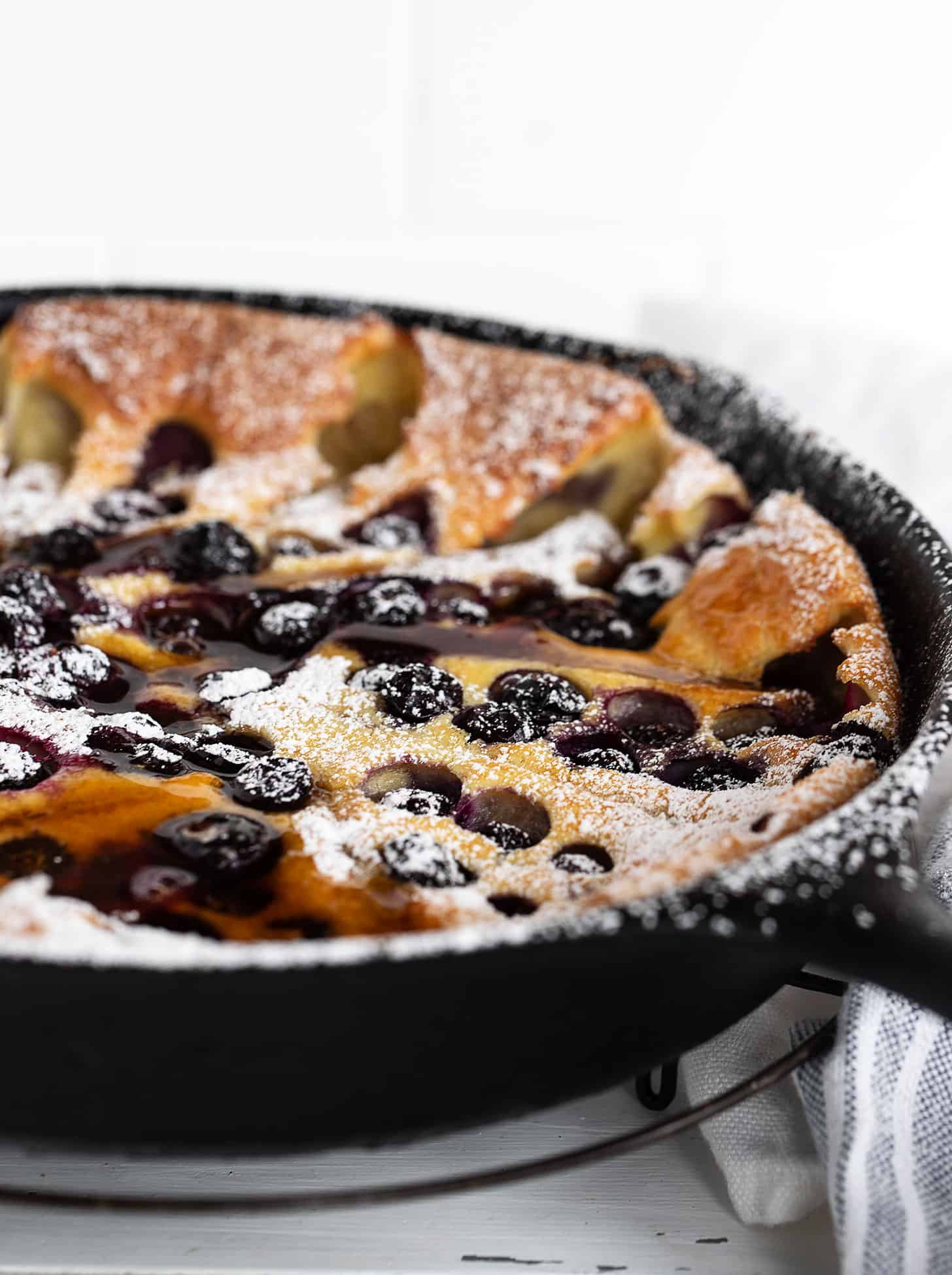 blueberry Dutch baby with sausage in cast iron skillet