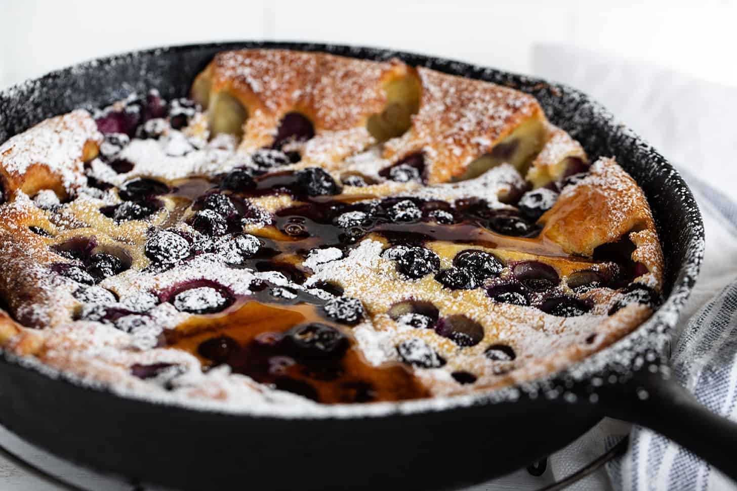 blueberry Dutch baby with sausage in cast iron skillet