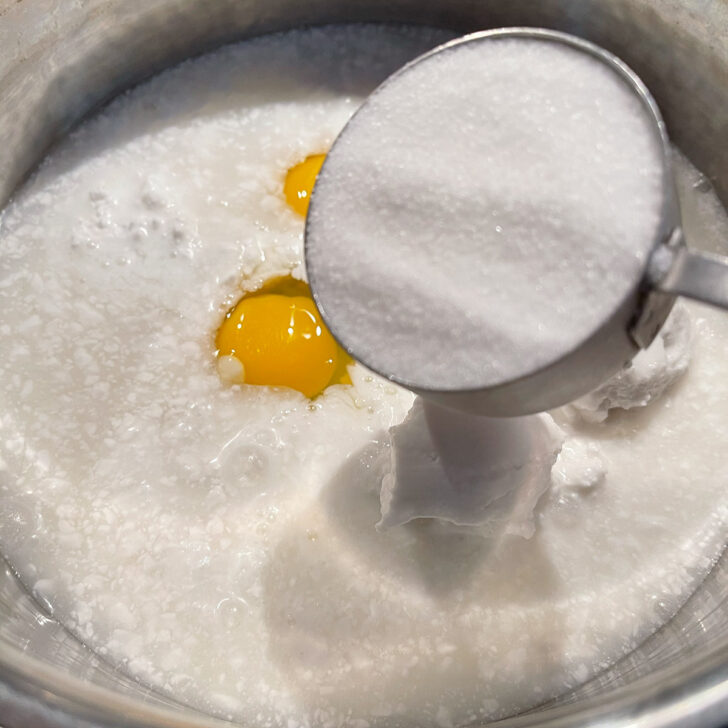 Adding the sugar and eggs to the saucepan.