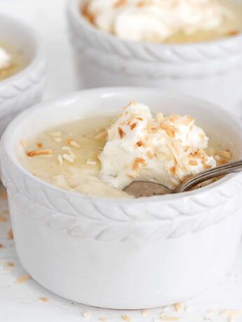 coconut cream pudding in ramekins with whipped cream on top