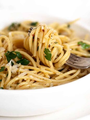 spaghetti with olive oil and garlic in white bowl with fork