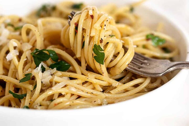 spaghetti with olive oil and garlic in white bowl with fork