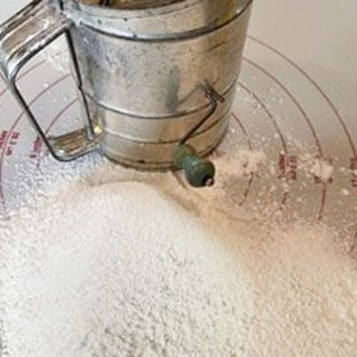 Sifting the flour with a sifter onto parchment paper.