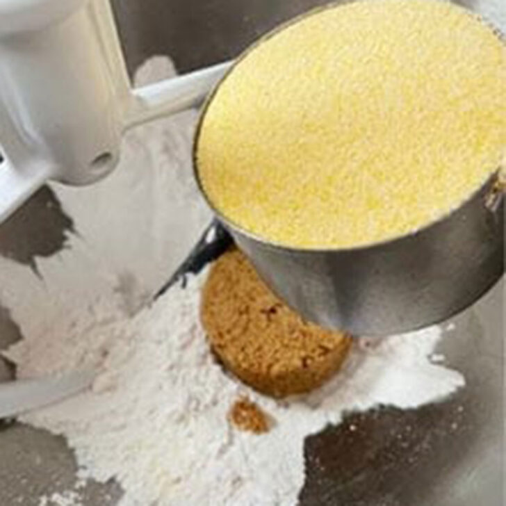 Adding the cornmeal to the mixing bowl.
