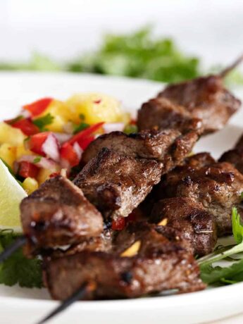 jerk pork skewers on plate with pineapple salsa