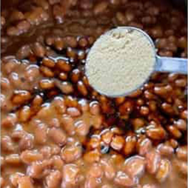 Adding powdered mustard to the pork and beans mixture.