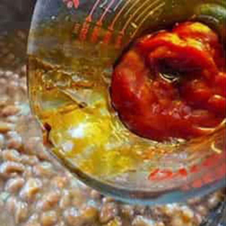Adding the ketchup to the pork and beans mixture.