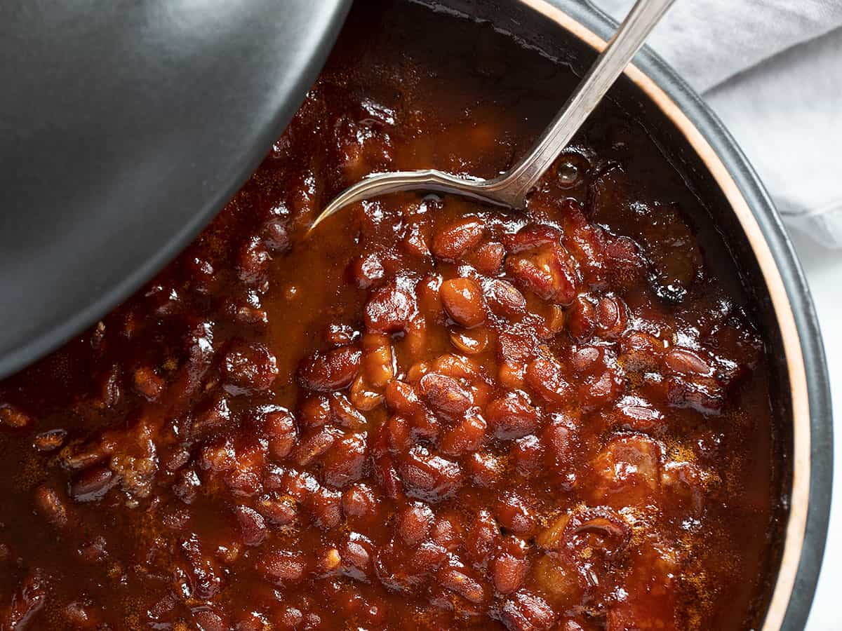 baked beans in black casserole dish with spoon