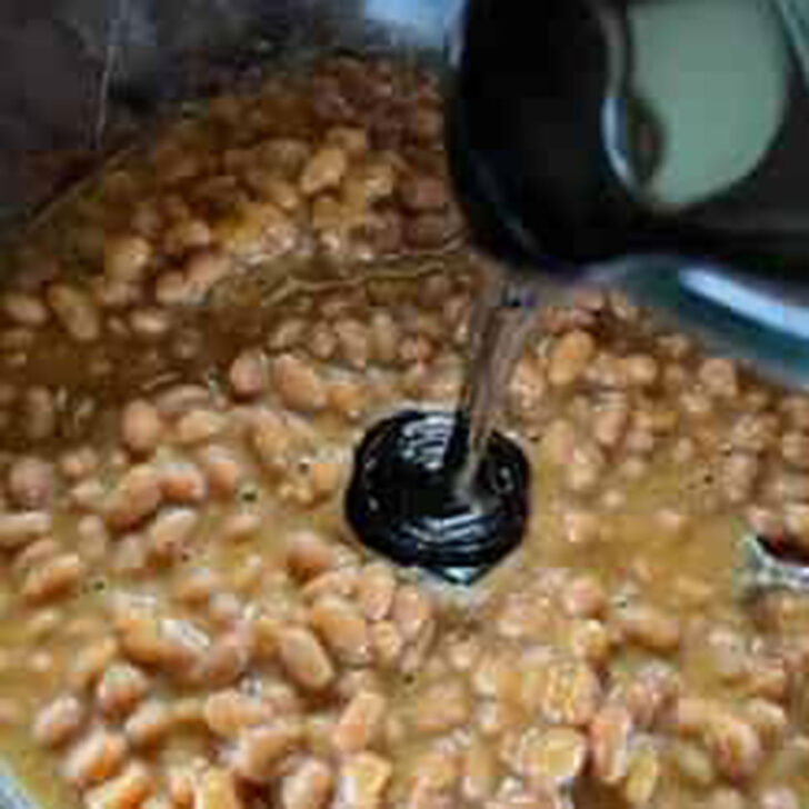 Adding molasses to canned pork and beans.