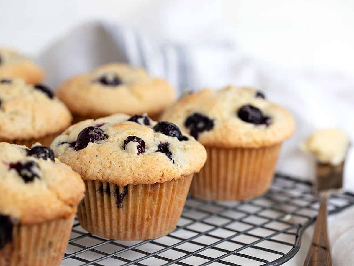 blueberry muffins on cooling rack with knife and butter