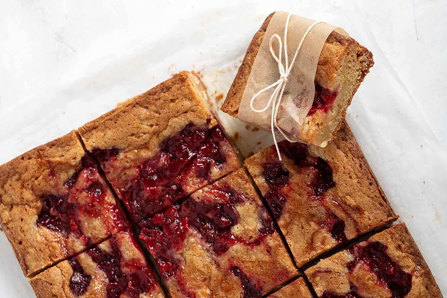 strawberry and white chocolate blondies sliced on parchment paper