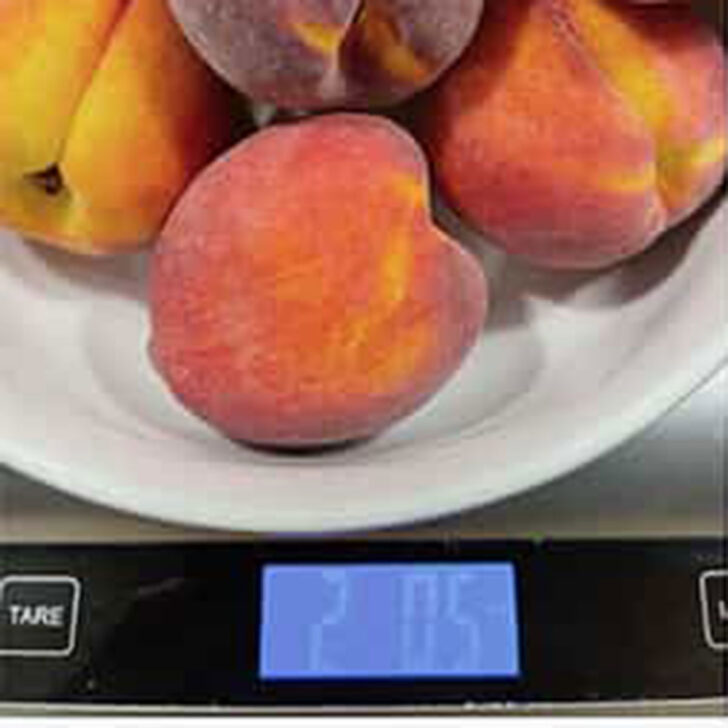 Weighing whole peaches on a scale.