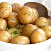 salt potatoes in bowl with melted butter and herbs